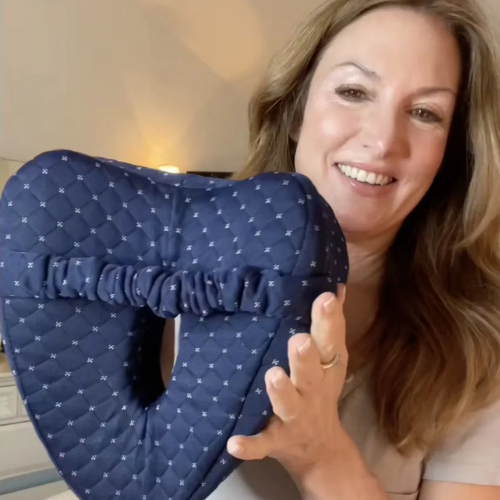 לקוחה מחזיקה את כרית הברכיים האורטופדית Laila Lite בצבע כחול – פתרון טבעי להקלה על כאבי גב ואגן בזמן שינה